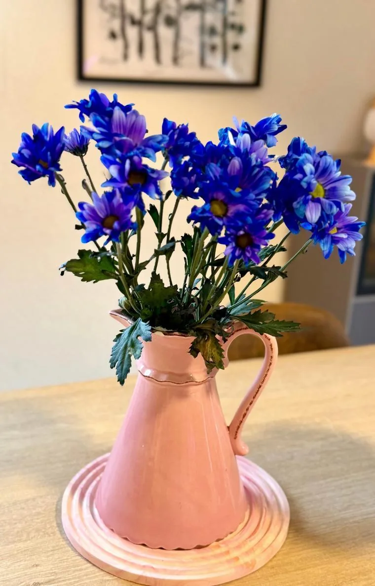 Ein rosafarbener Krug, blaue Blumen und ein Jesmonite-Tablett.